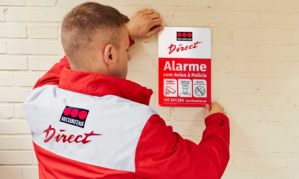 Técnico da Securitas Direct instalando placa dissuasora numa casa, reforçando a importância da segurança residencial.