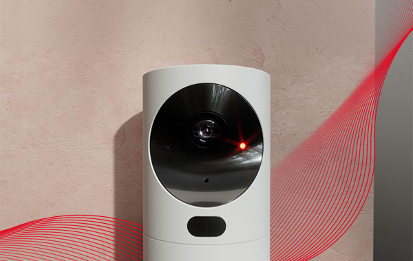 Fotodetetor do alarme da Verisure de corpo branco colocado numa parede bege e com a aura vermelha em redor